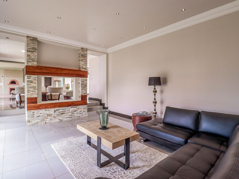 Spacious living room featuring a modern stone-clad feature wall with a timber mantelpiece, recessed downlights, and polished tiled flooring.