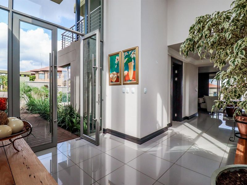 Spacious entrance hall featuring double-volume glass doors, high ceilings, and polished porcelain floor tiles, creating a bright and welcoming transition into the home.