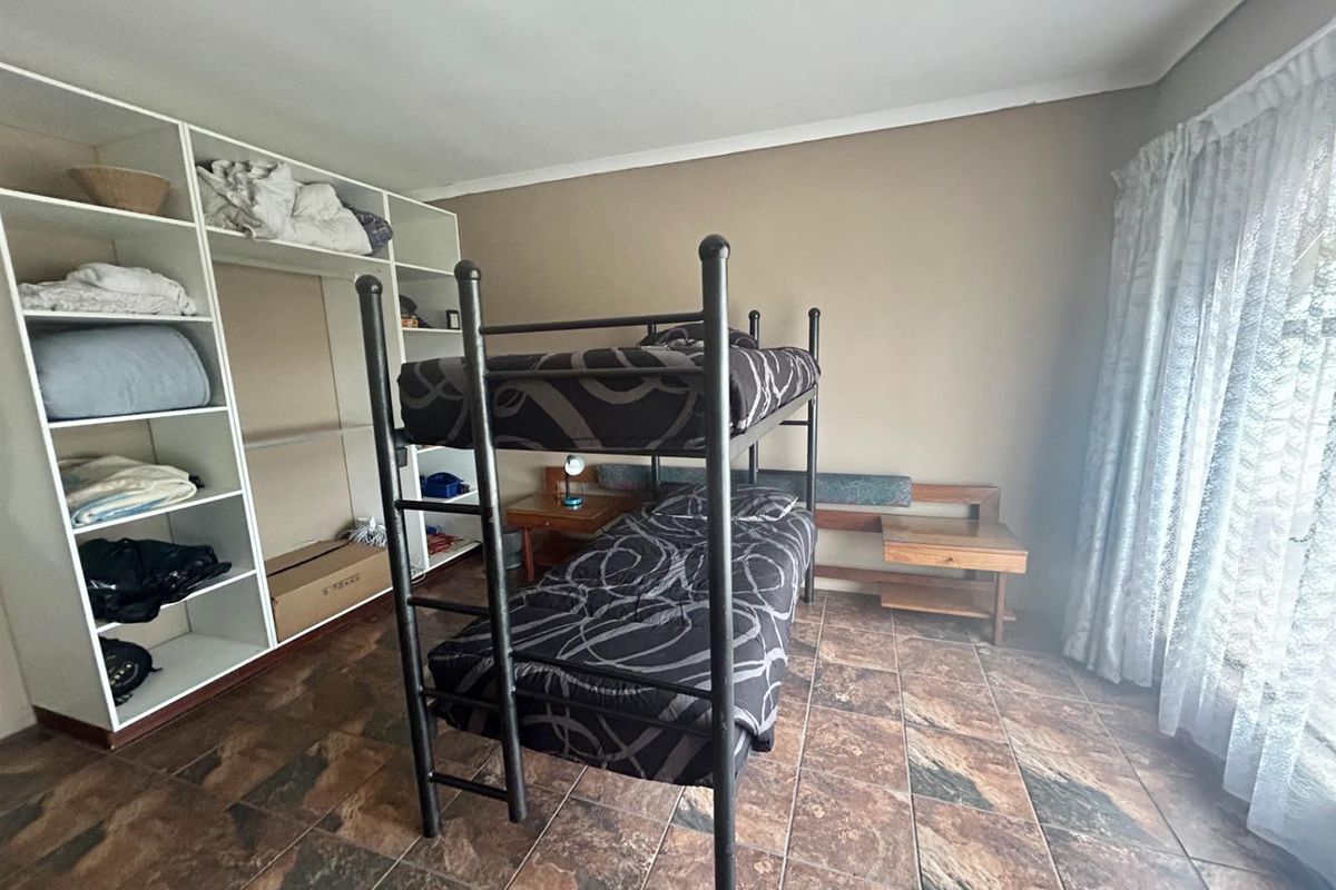 A functional bedroom featuring built-in shelving units and tiled flooring, providing practical storage and living space.