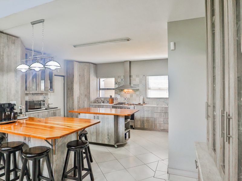 Spacious kitchen featuring a large wooden island, modern cabinetry, gas hob with extractor fan, and tiled flooring in an open-plan layout.