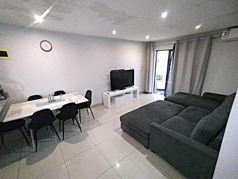 Open-plan living and dining area featuring tiled flooring, recessed lighting, and access to a balcony through a sliding glass door.