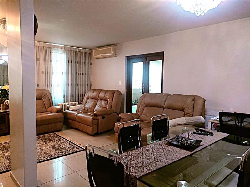 Open-plan living and dining area featuring tiled flooring, split-system air conditioning, and access to an outdoor space through double glass doors.