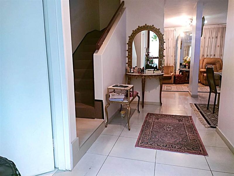 A bright entrance hallway featuring tiled flooring and a staircase leading to the upper level, with an open transition into the living area.