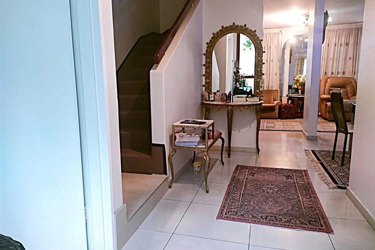 A bright entrance hallway featuring tiled flooring and a staircase leading to the upper level, with an open transition into the living area.