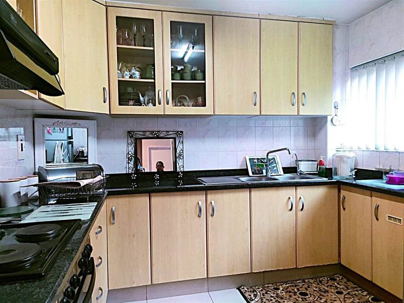 Functional kitchen featuring light wood-finish cabinetry, dark granite countertops, a built-in hob, and an extractor fan with a tiled backsplash.