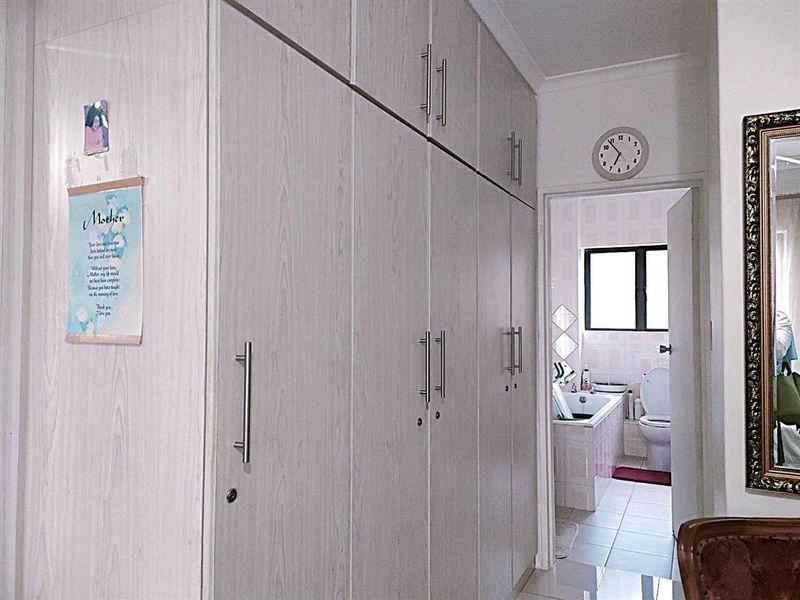 Bedroom featuring extensive floor-to-ceiling built-in cupboards with light wood-grain finish and direct access to an en-suite bathroom.