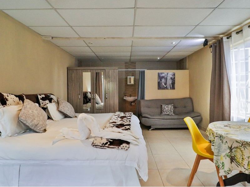 A bedroom featuring a drop ceiling, tiled flooring, and an integrated basin area, offering a functional layout for guest accommodation.