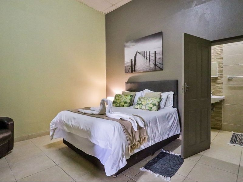 A bedroom featuring tiled flooring and direct access to an en-suite bathroom, providing a functional layout for guest accommodation.