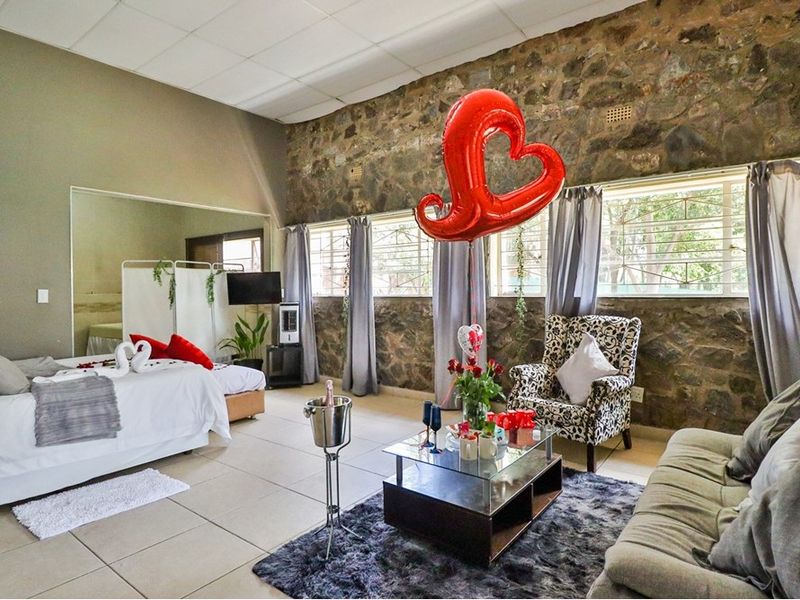 Spacious bedroom featuring an exposed stone feature wall, tiled flooring, and a drop ceiling, offering a unique rustic aesthetic.