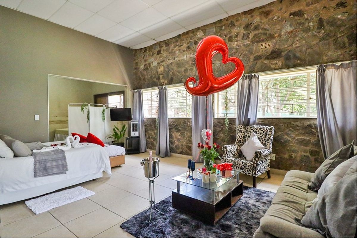 Spacious bedroom featuring an exposed stone feature wall, tiled flooring, and a drop ceiling, offering a unique rustic aesthetic.