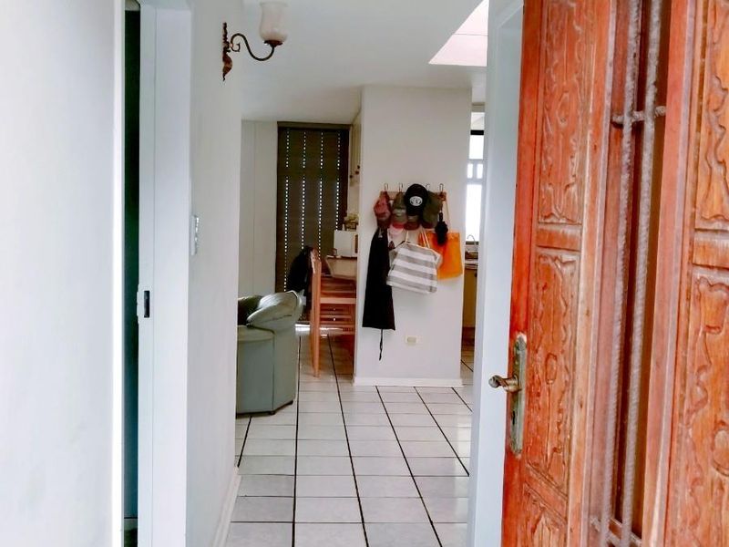Entryway featuring tiled flooring and a traditional timber front door, leading into an open-plan living area.