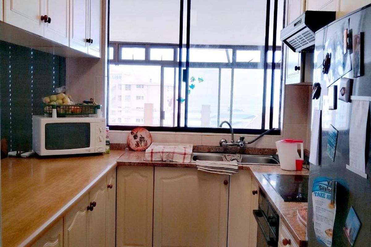 A functional galley-style kitchen featuring laminate countertops, built-in cabinetry, an integrated oven and hob, and a double basin sink with a window view.