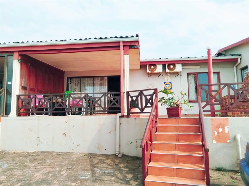 Front exterior view of the apartment featuring a covered patio, tiled staircase with timber railings, and wall-mounted air conditioning units.