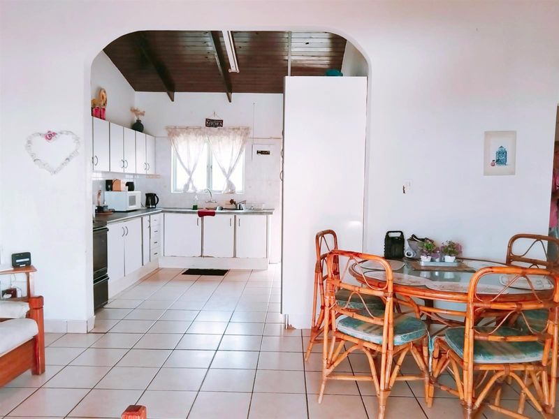 Open-plan kitchen and dining area featuring tiled flooring, exposed timber ceiling, and functional built-in cabinetry.