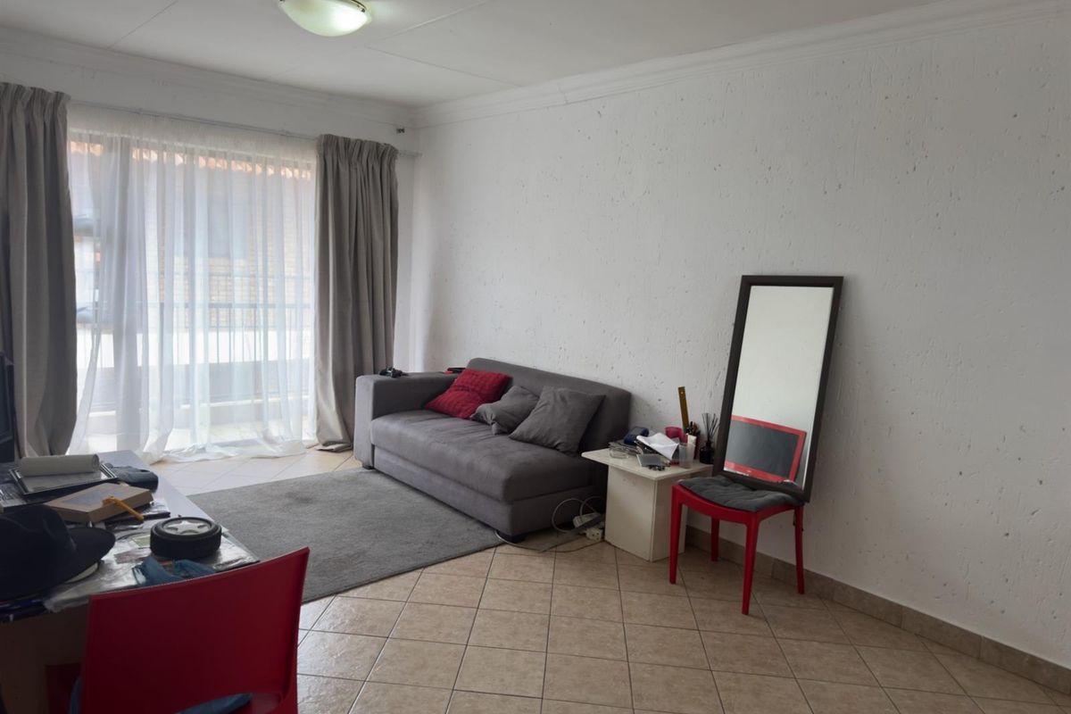 A living room featuring tiled flooring and a large sliding glass door providing access to an outdoor area.
