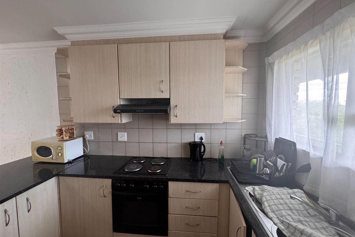 Functional kitchen featuring light wood-finish cabinetry, granite countertops, a built-in oven with hob, and a tiled backsplash.