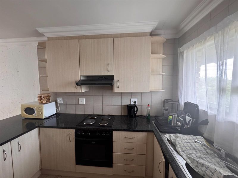 Functional kitchen featuring light wood-finish cabinetry, granite countertops, a built-in oven with hob, and a tiled backsplash.
