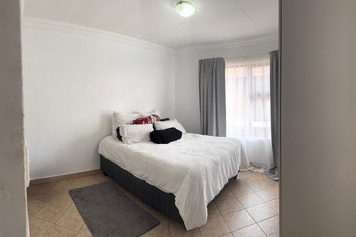 A bedroom featuring tiled flooring, ceiling cornice, and a central light fixture, offering a neutral base for personalization.