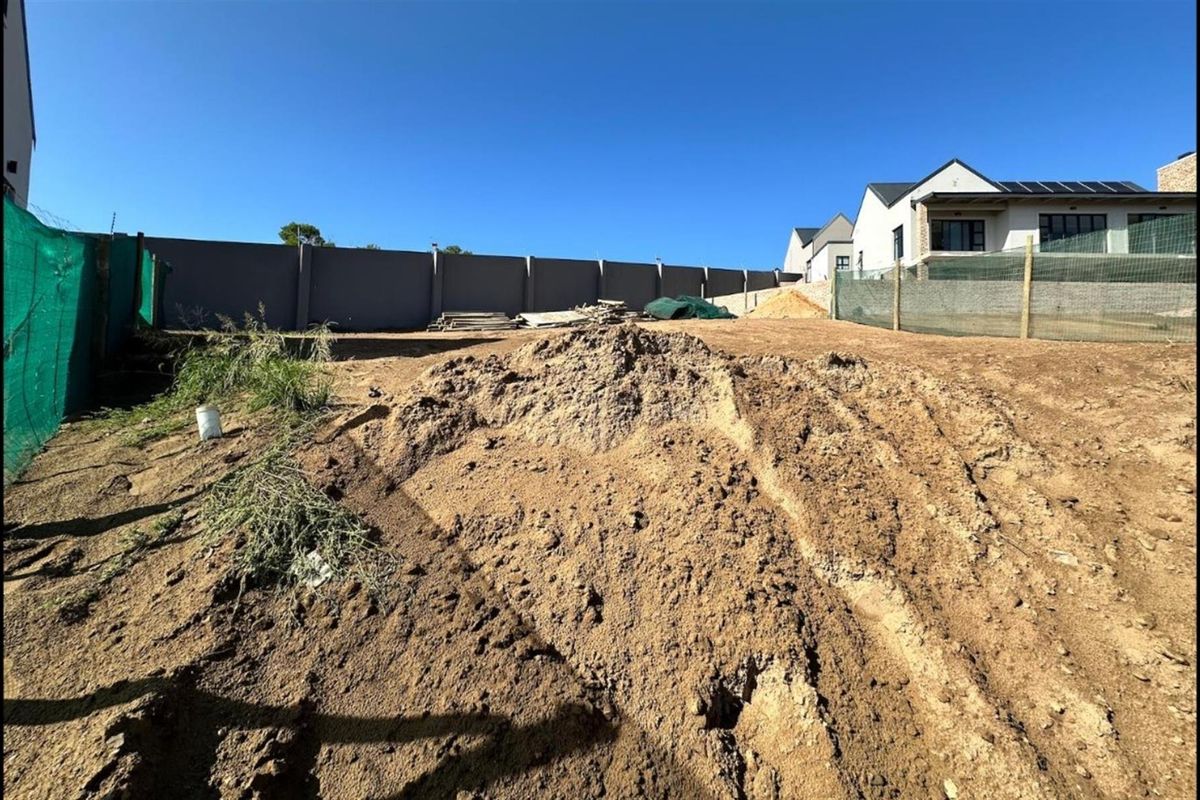 A vacant residential plot featuring perimeter boundary walls and cleared earth, ready for development in a established neighborhood.