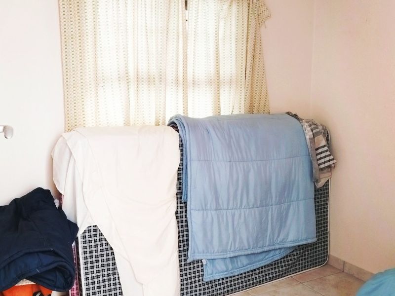 A simple bedroom featuring tiled flooring and a ceiling vent, providing a blank canvas for potential interior design and furnishing.