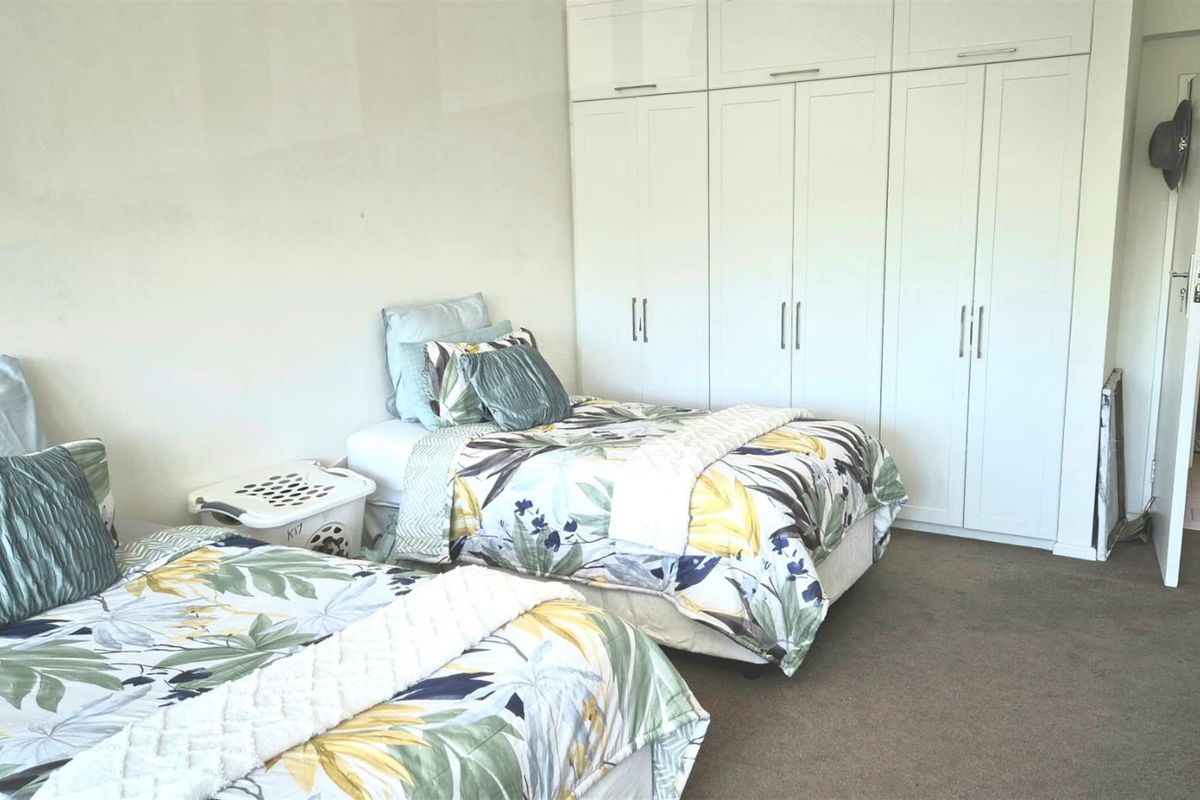A bedroom featuring built-in floor-to-ceiling white cabinetry and carpeted flooring.