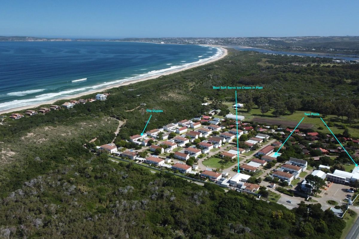 Aerial view of the residential complex situated near the coastline, featuring communal swimming pools and proximity to the beach.
