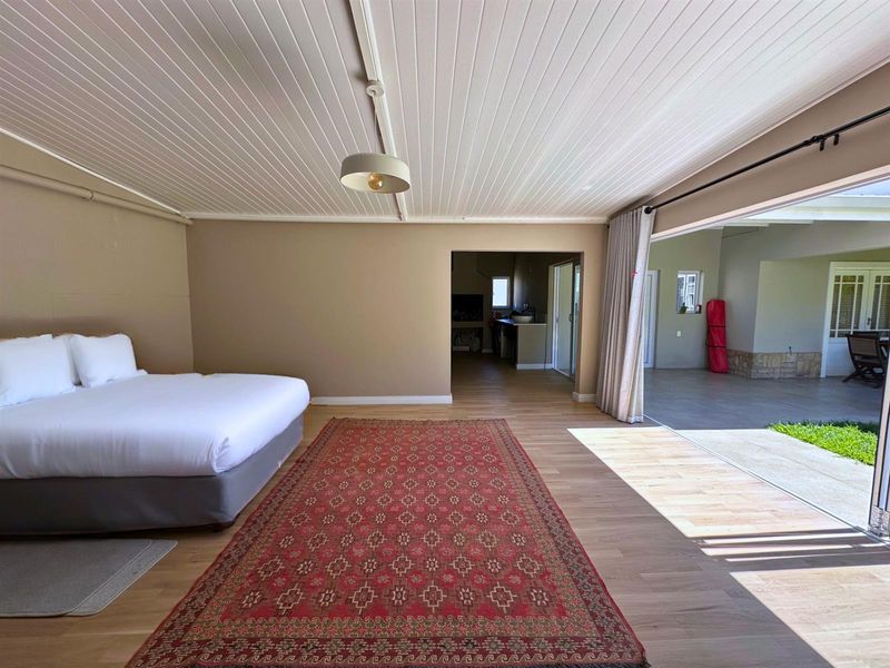 Spacious bedroom featuring timber-look flooring, a tongue and groove ceiling, and large sliding glass doors that open onto an outdoor patio area.