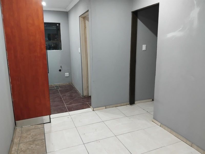 An empty hallway featuring tiled flooring and multiple internal doorways, currently requiring minor finishing touches to the walls and trim.