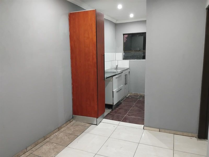 A compact kitchen area featuring basic cabinetry, a stainless steel sink, and tiled flooring, offering a functional space ready for modernization.
