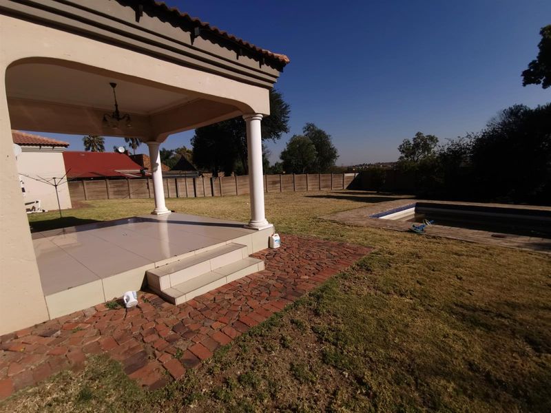 Spacious covered patio overlooking a private backyard with a swimming pool and perimeter walling.