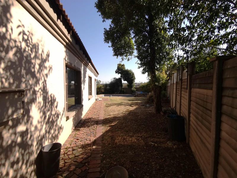 A side garden pathway featuring brick paving, leading towards the rear yard with a swimming pool and established trees.