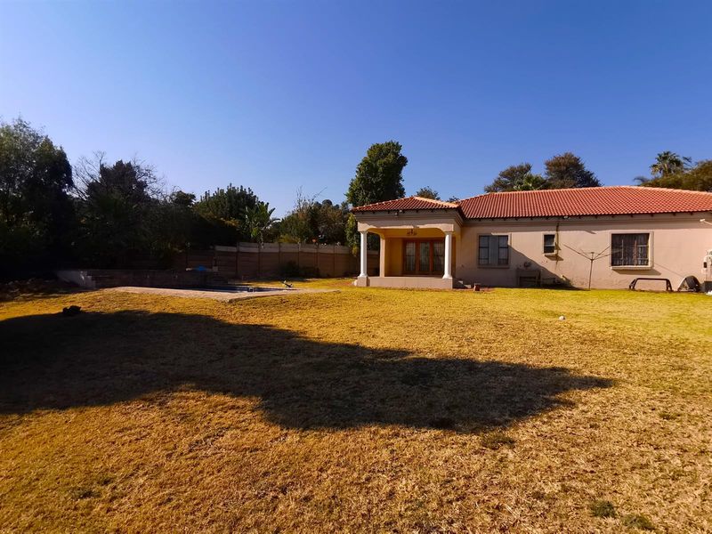 Spacious rear garden featuring a swimming pool, covered patio with columns, and a well-maintained lawn area.