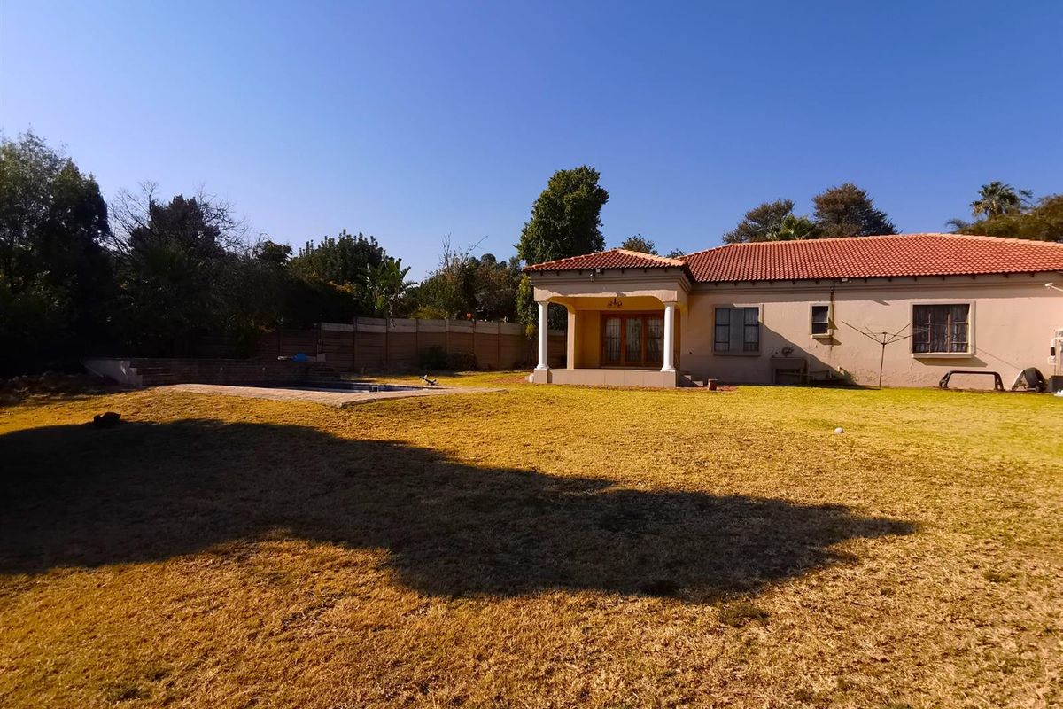 Spacious rear garden featuring a swimming pool, covered patio with columns, and a well-maintained lawn area.