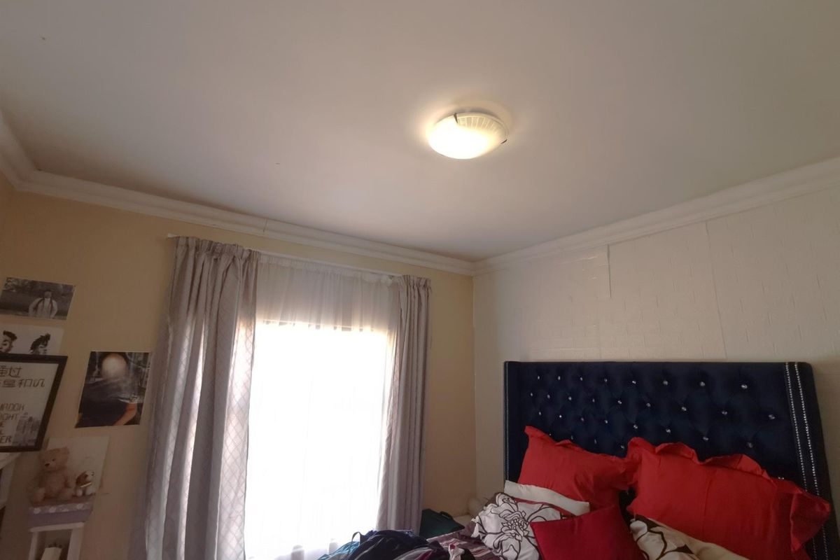 A bedroom featuring a central ceiling light fixture, crown molding, and a window with curtain tracks.