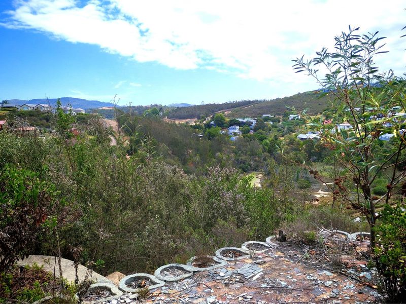 A scenic elevated view overlooking a valley and residential neighborhood, featuring a weathered retaining wall in the foreground.