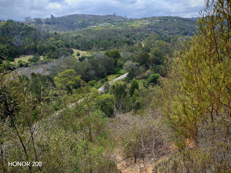 A scenic elevated view overlooking a lush, green valley with rolling hills and natural vegetation.