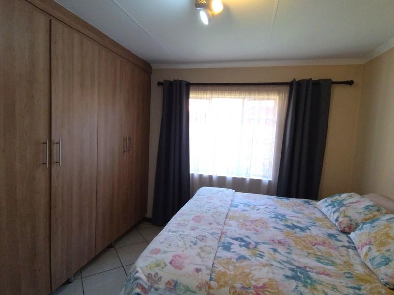 A bedroom featuring tiled flooring and a large built-in wooden wardrobe, providing ample storage space.