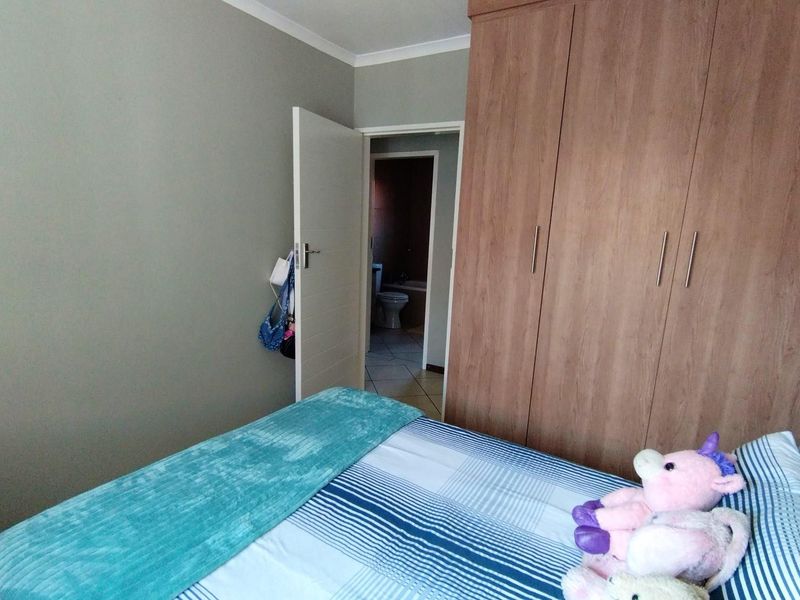 A bedroom featuring a large built-in wooden wardrobe and direct access to an en-suite bathroom.