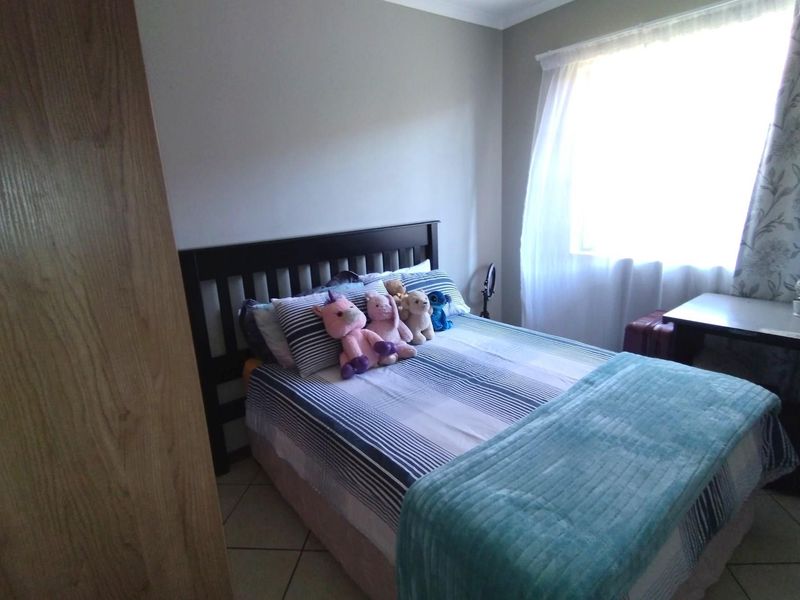 A functional bedroom featuring tiled flooring and a built-in cupboard, offering a comfortable space with natural light.