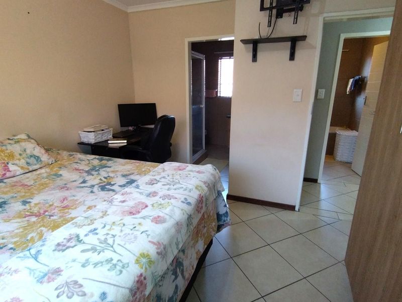 Bedroom featuring tiled flooring, built-in cupboard storage, and direct access to an en-suite bathroom.