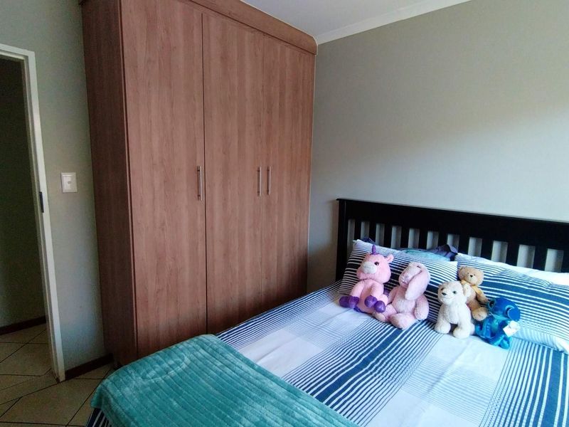 A bedroom featuring a built-in wooden wardrobe and tiled flooring, providing functional storage space.