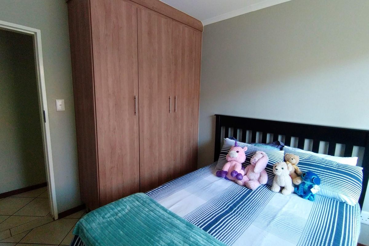 A bedroom featuring a built-in wooden wardrobe and tiled flooring, providing functional storage space.