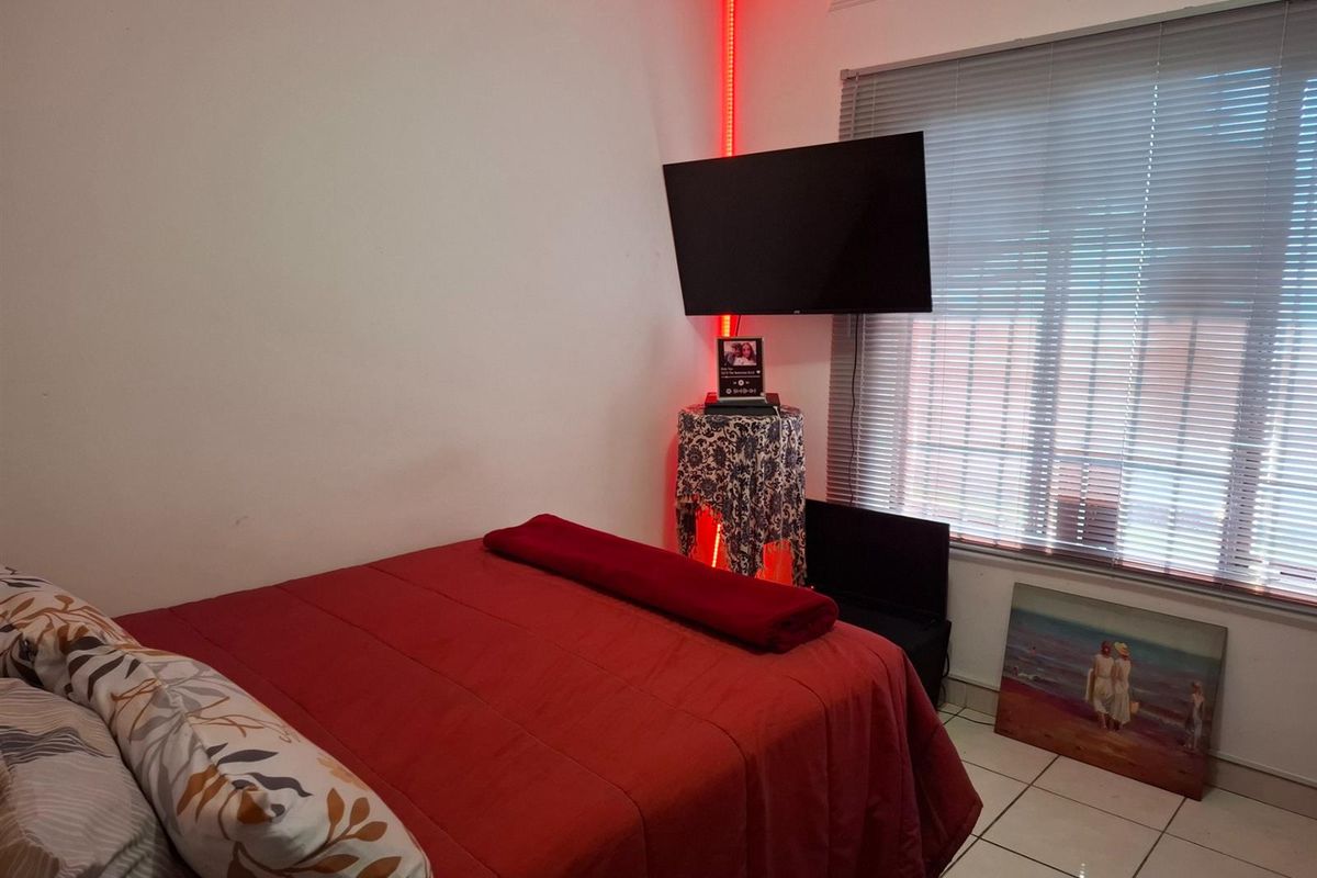 A bedroom featuring tiled flooring and a window with fitted blinds.