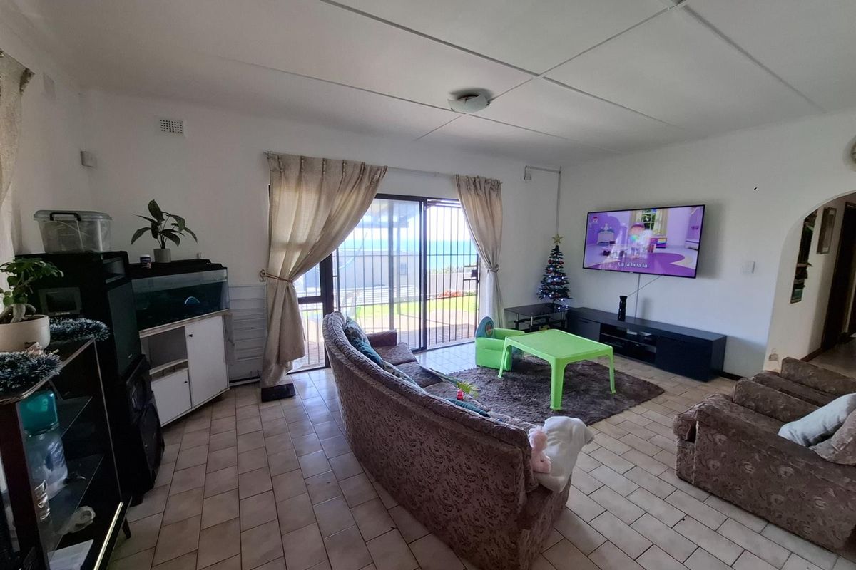 Spacious living room featuring tiled flooring, large sliding glass doors leading to an outdoor area, and a wall-mounted television setup.