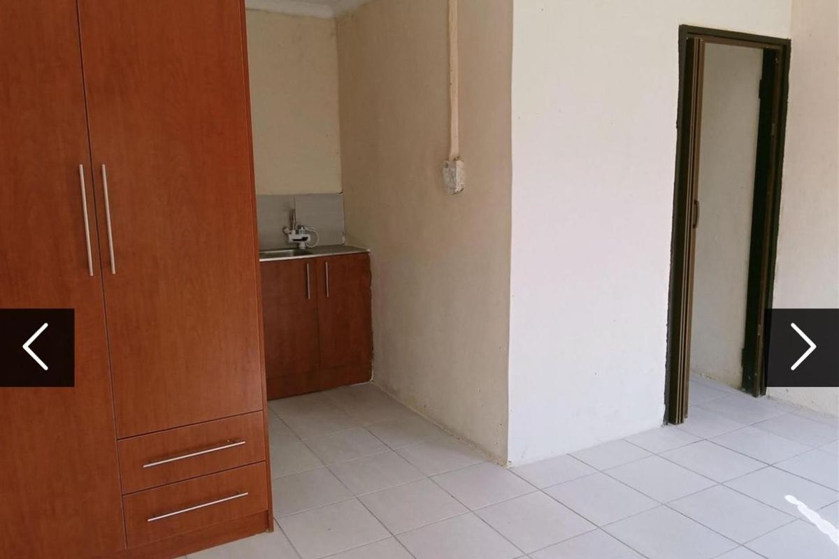 A compact kitchen area featuring a small sink unit, built-in cabinetry, and tiled flooring, requiring cosmetic updates to improve the overall finish.