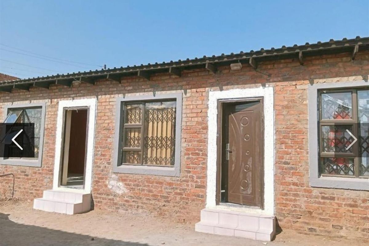 Exterior view of a single-story brick building featuring multiple entrances with security doors and aluminium windows under a corrugated metal roof.