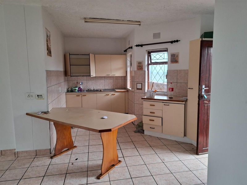 A dated kitchen featuring tiled flooring, laminate cabinetry, and a tiled backsplash, offering a functional layout ready for modernization.