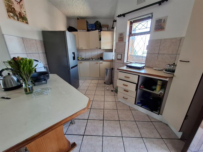A functional kitchen featuring tiled flooring, built-in cabinetry, and a breakfast counter, offering a practical layout with potential for modernization.