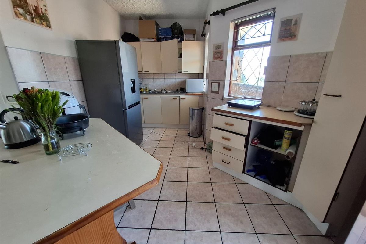 A functional kitchen featuring tiled flooring, built-in cabinetry, and a breakfast counter, offering a practical layout with potential for modernization.