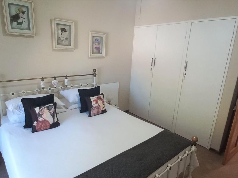 A bedroom featuring built-in cupboards and direct access to an adjoining bathroom with tiled flooring.